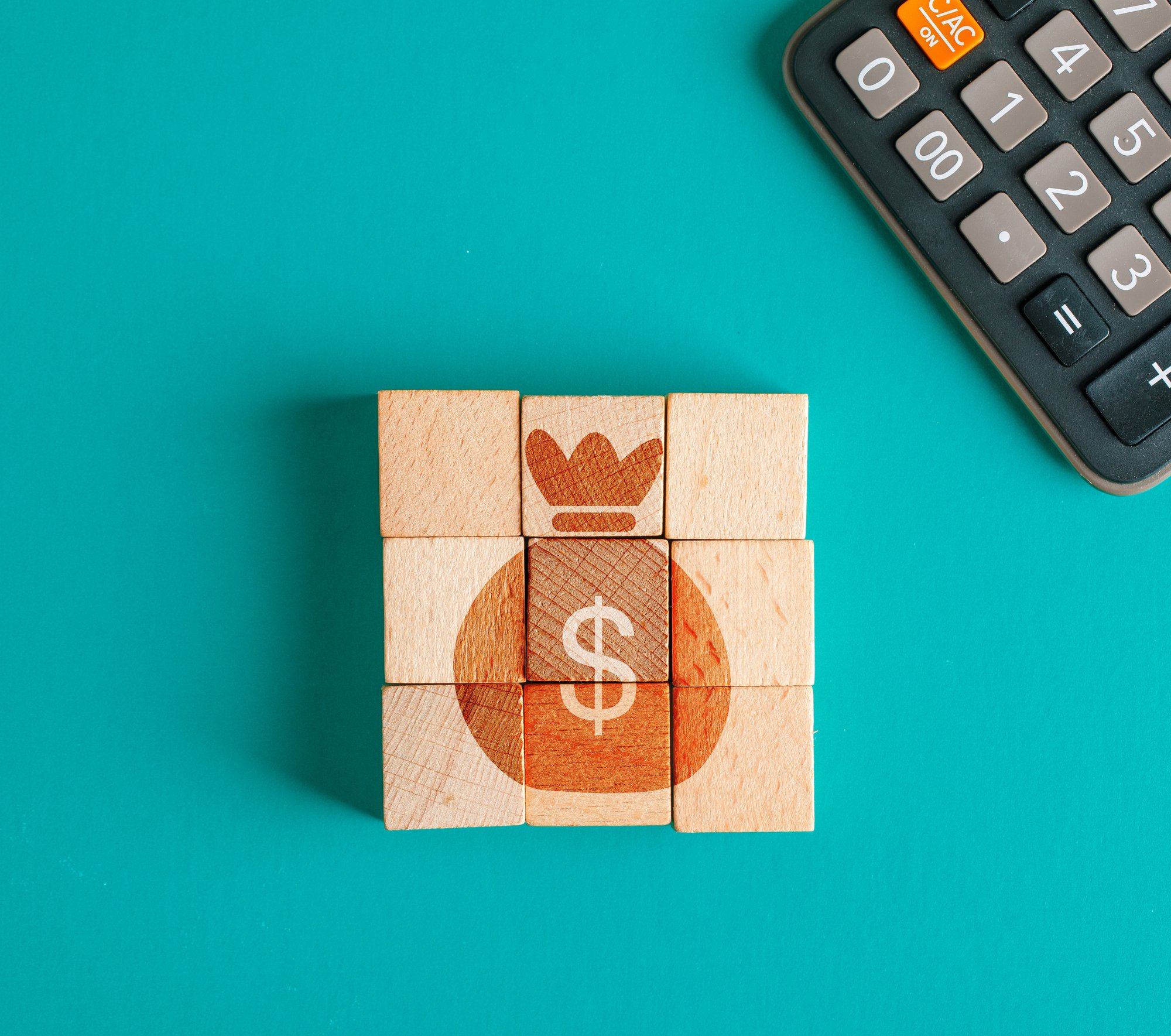 financial-concept-with-icon-wooden-cubes-calculator-turquoise-table-flat-lay